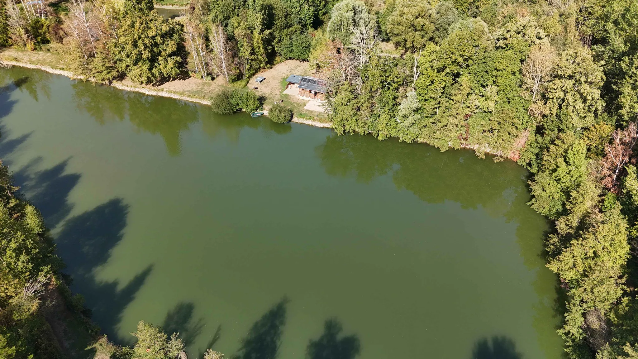 Vue aérienne de la cabane au bord de son étang privé, entouré d’arbres