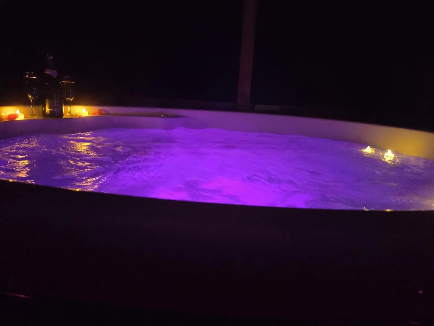 Le bain nordique illuminé en violet avec des bougies sur le rebord
